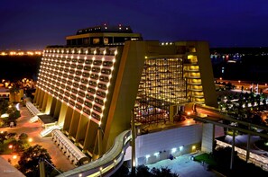 A modern hotel with a distinctive curved facade, multiple floors, and a central atrium. - Disney's Contemporary Resort (Lake Buena Vista)