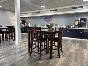 A breakfast area with a table and chairs, a kitchen counter with appliances, and a sign reading 'Baymont Breakfast Corner'.
