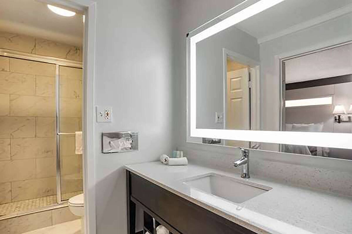 A modern bathroom with a glass shower enclosure, a large mirror, and a vanity with a sink.