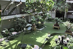 Un jardín interior con iluminación artificial, zonas de estar y plantas en macetas.