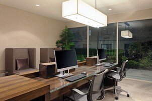 Un espacio de oficina moderno con escritorios de vidrio, sillas ergonómicas y múltiples monitores de ordenador.