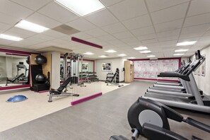 Un gimnasio con cintas de correr, máquinas de pesas y pelotas de ejercicio.