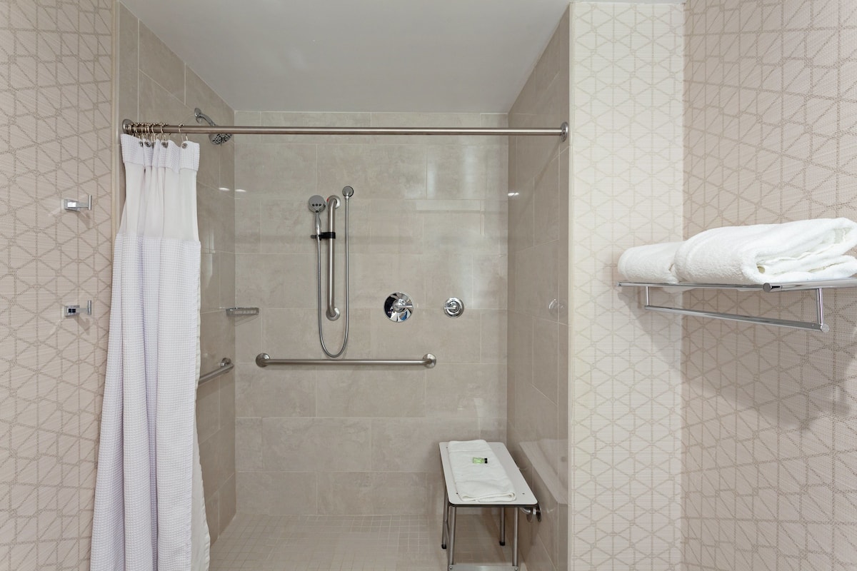 A shower area with a glass door, a towel rack, and a small table with a towel.