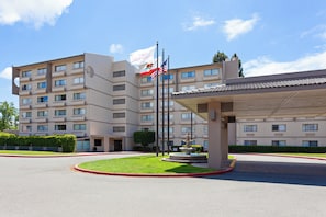 A multi-story hotel with a central courtyard, a fountain, and a flagpole with flags. - Crowne Plaza Silicon Valley N - Union City by IHG (Union City)