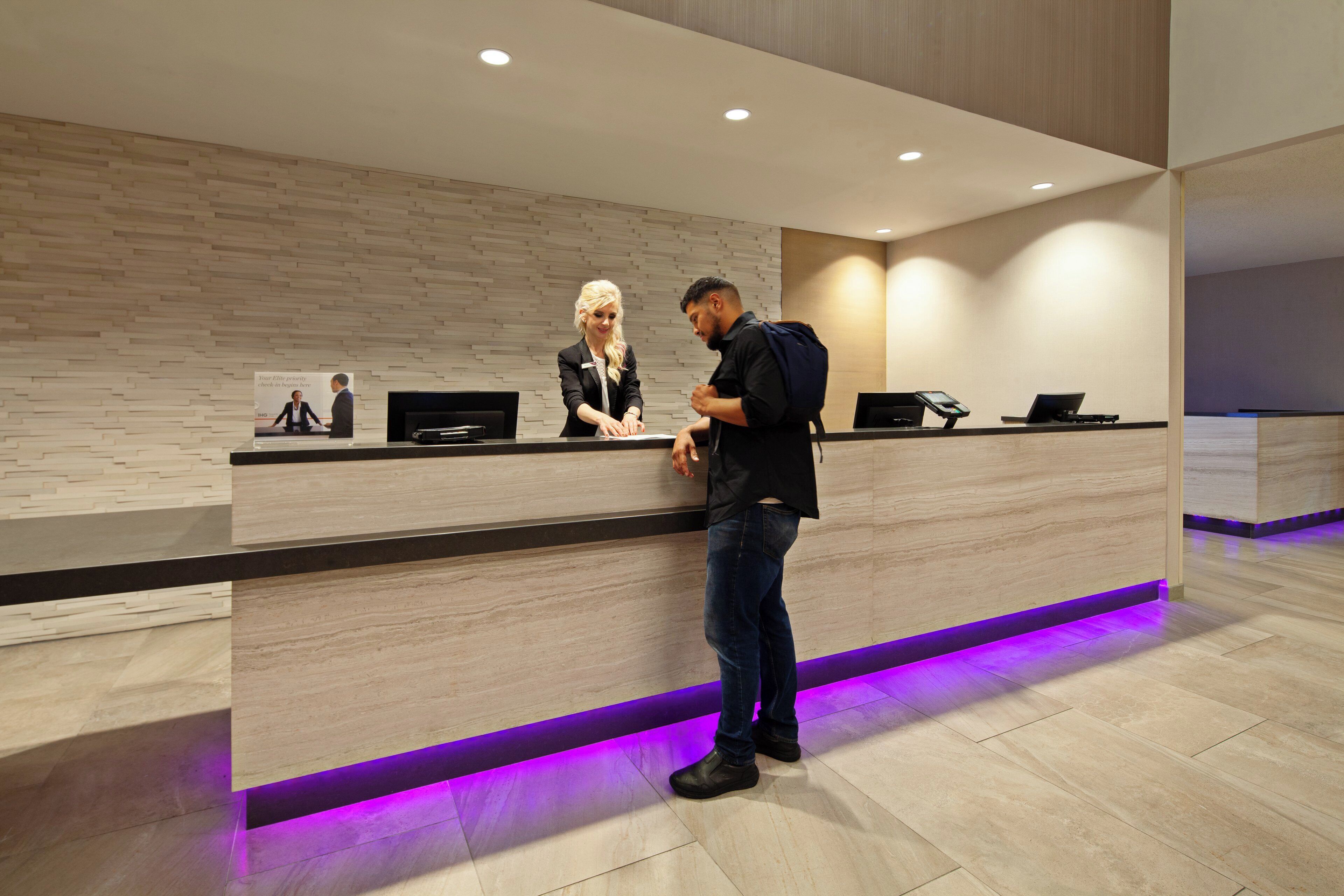 A reception desk with a modern design, a digital screen, and a check-in counter.