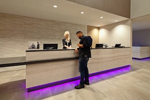 A reception desk with a modern design, a digital screen, and a check-in counter. - Crowne Plaza Silicon Valley N - Union City by IHG (Union City)