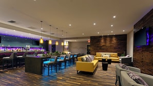 Un área de lounge moderna con bar, asientos y un televisor de pantalla plana montado en una pared de madera.