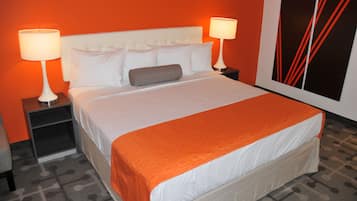 A hotel room with a large bed, two bedside tables with lamps, a red accent wall, and a geometric patterned carpet.