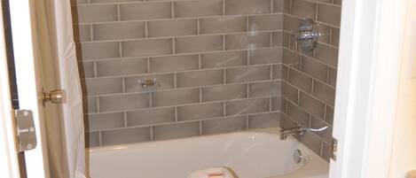 Un baño con bañera, inodoro y paredes de azulejos.