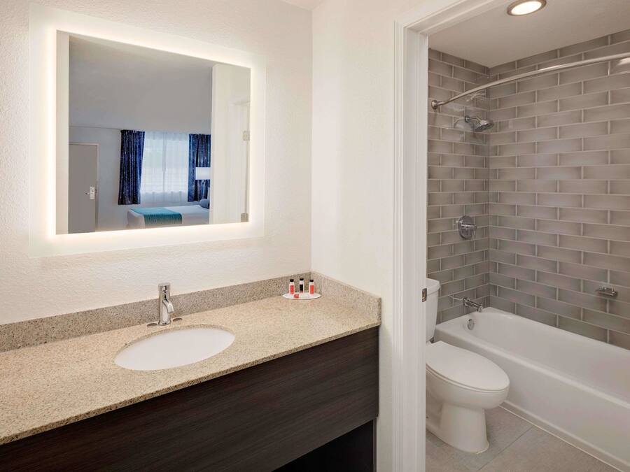 A bathroom with a double sink, a mirror, a shower, and a toilet.