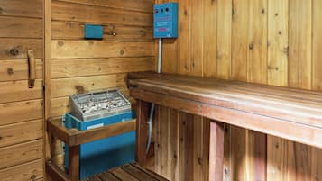A wooden sauna with a bench, a heater, and a control panel.