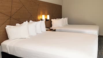 A hotel room with two beds, a wooden headboard, bedside lamps, and a telephone.