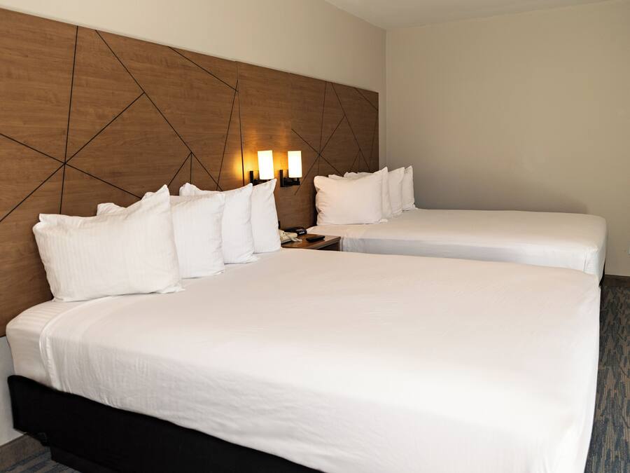 A hotel room with two beds, a wooden headboard, bedside lamps, and a telephone.