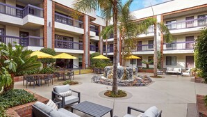 A courtyard with outdoor seating, palm trees, and a central rock feature. - Best Western Plus Meridian Inn & Suites, Anaheim-Orange (Orange)