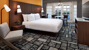 A hotel room with a large bed, a desk with a chair, a TV, and a view of the outdoors through a window. - Best Western Plus Meridian Inn & Suites, Anaheim-Orange (Orange)
