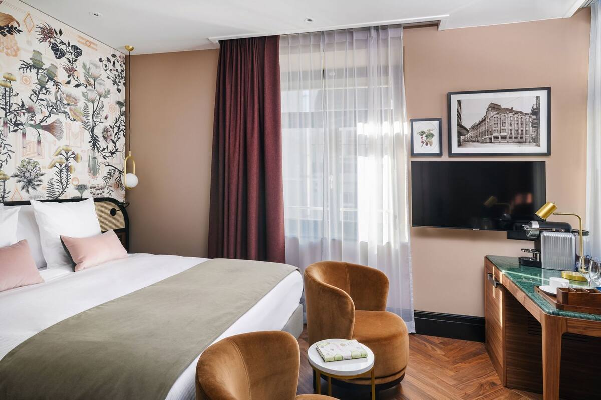 Une chambre d’hôtel équipée d’un lit, d’un bureau, d’une chaise, d’une télévision et d’une fenêtre avec des rideaux.