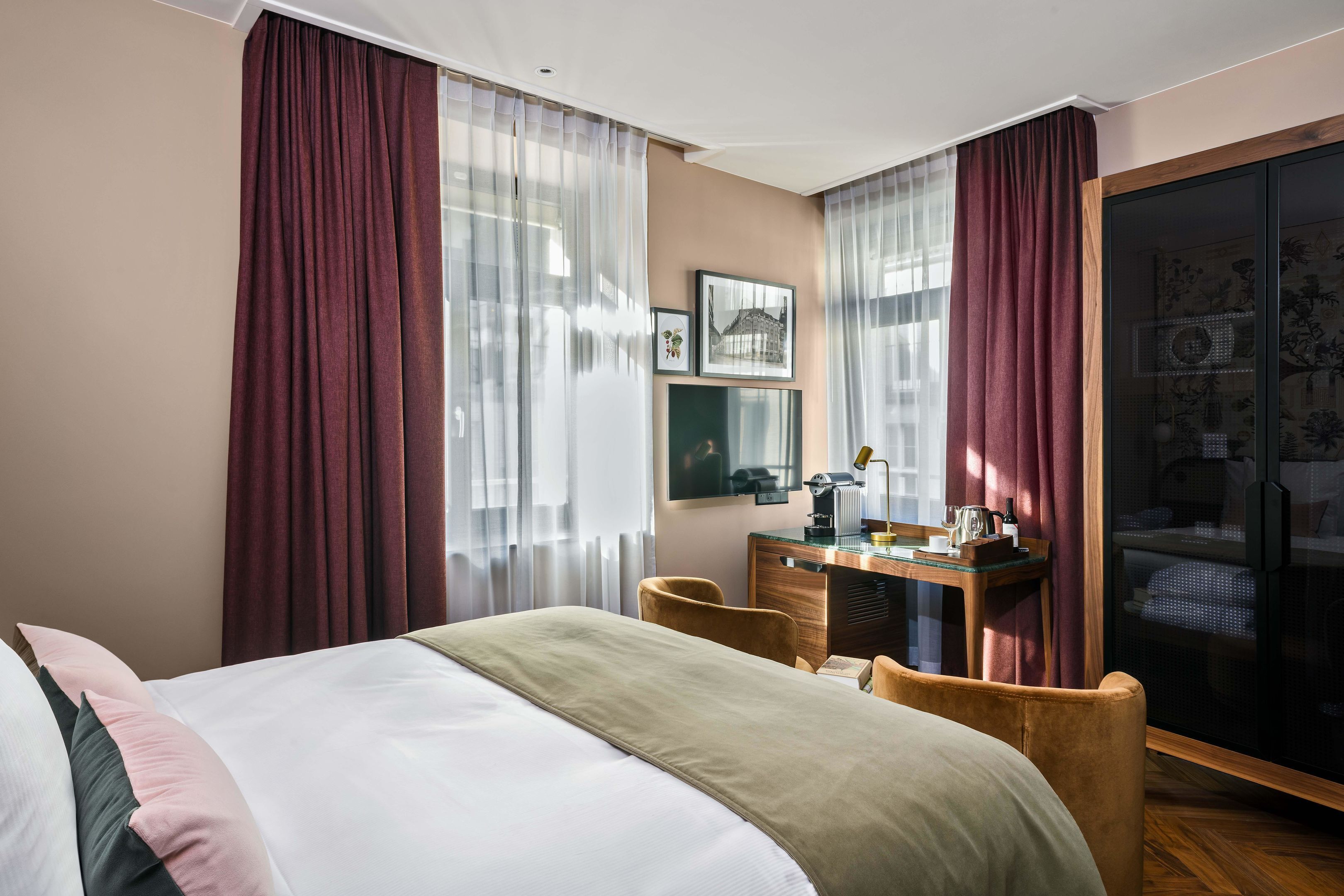 A hotel room with a bed, a desk, a chair, a television, and a sliding glass door.