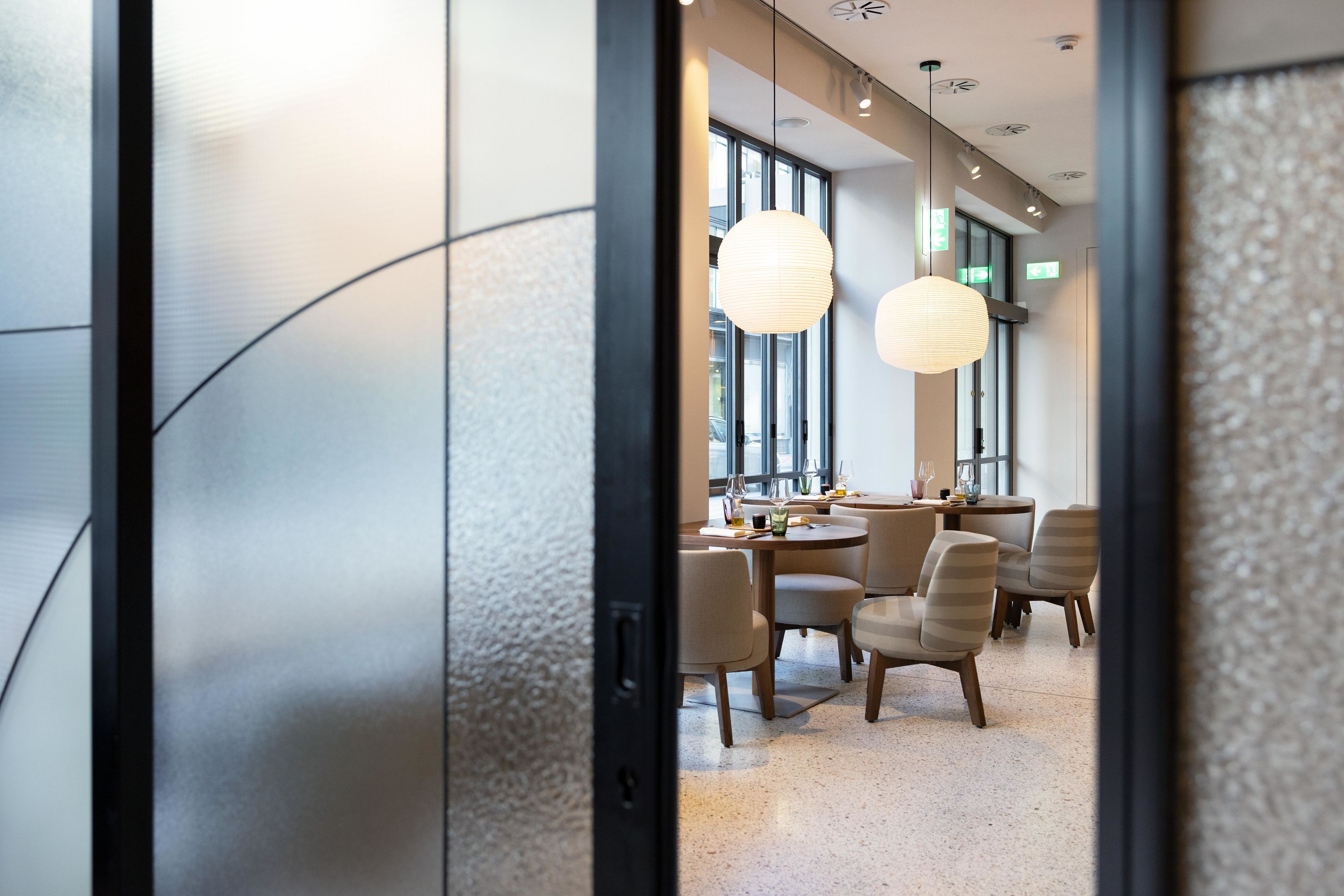 A modern dining area with round tables, chairs, and pendant lighting.
