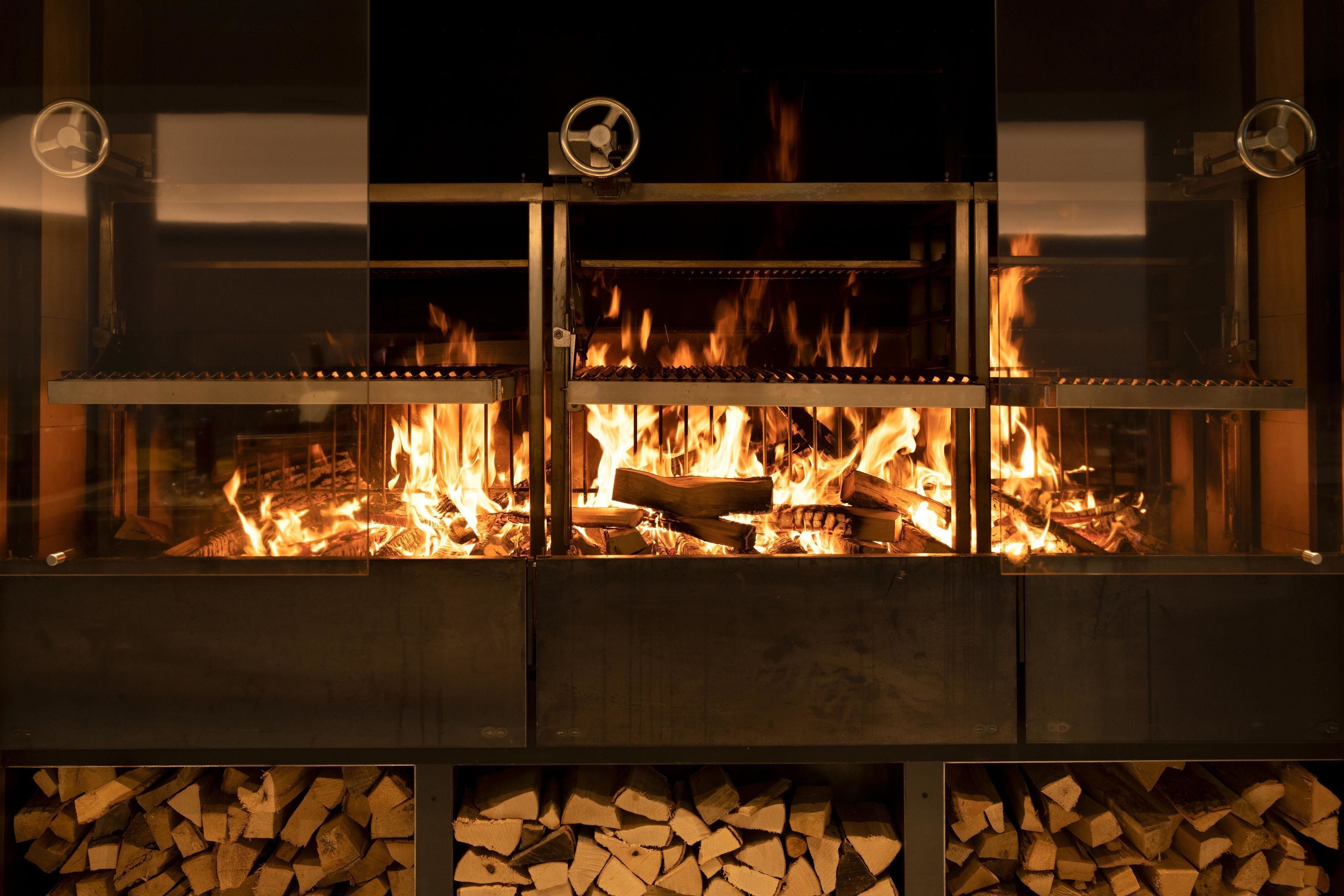 A fireplace with a glass front, logs inside, and a metal frame.