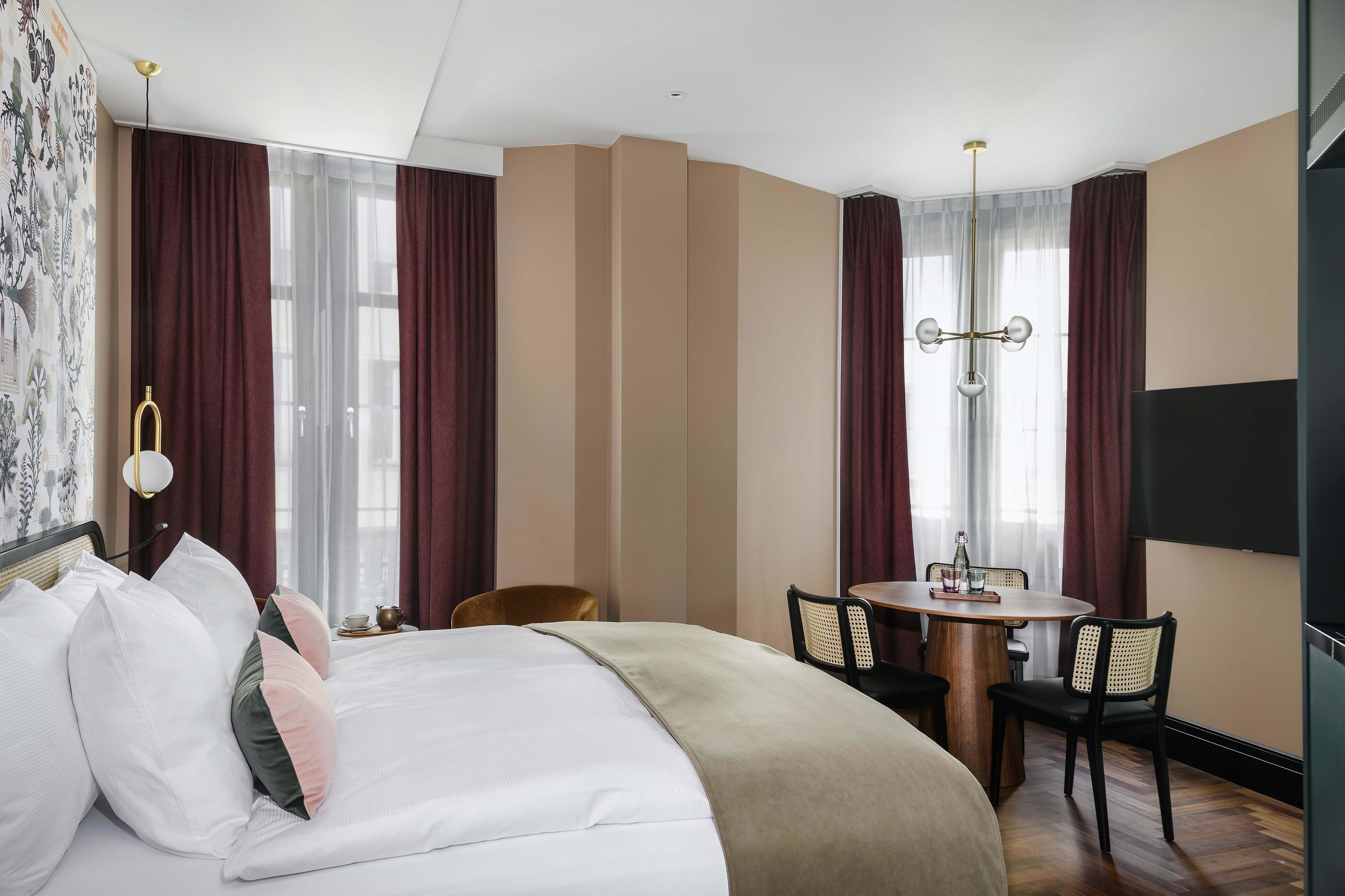 Une chambre d’hôtel comprenant un lit, une table à manger, des chaises, un lustre et un téléviseur.