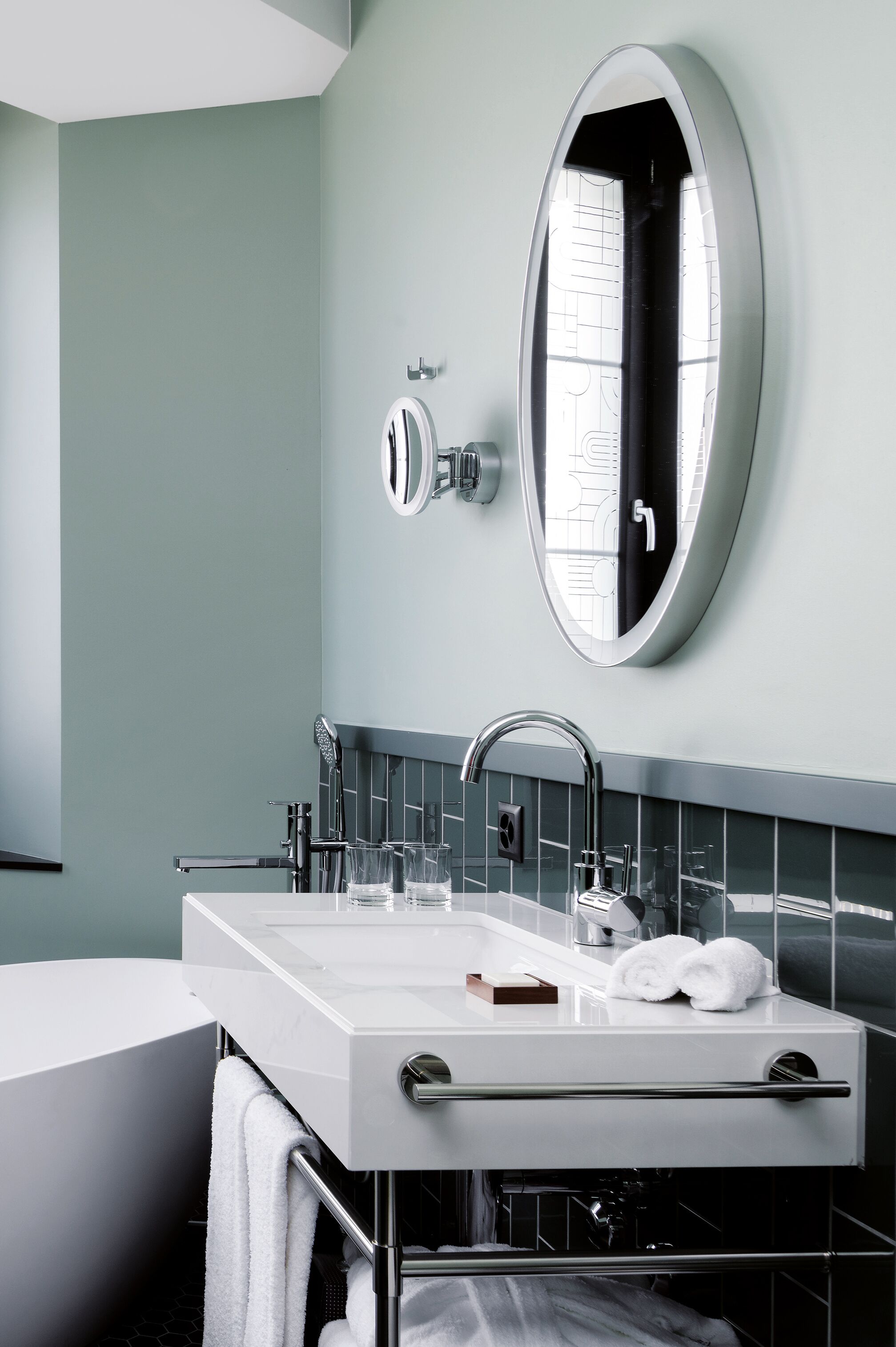 A modern bathroom with a white sink, a large mirror, and a towel rack.
