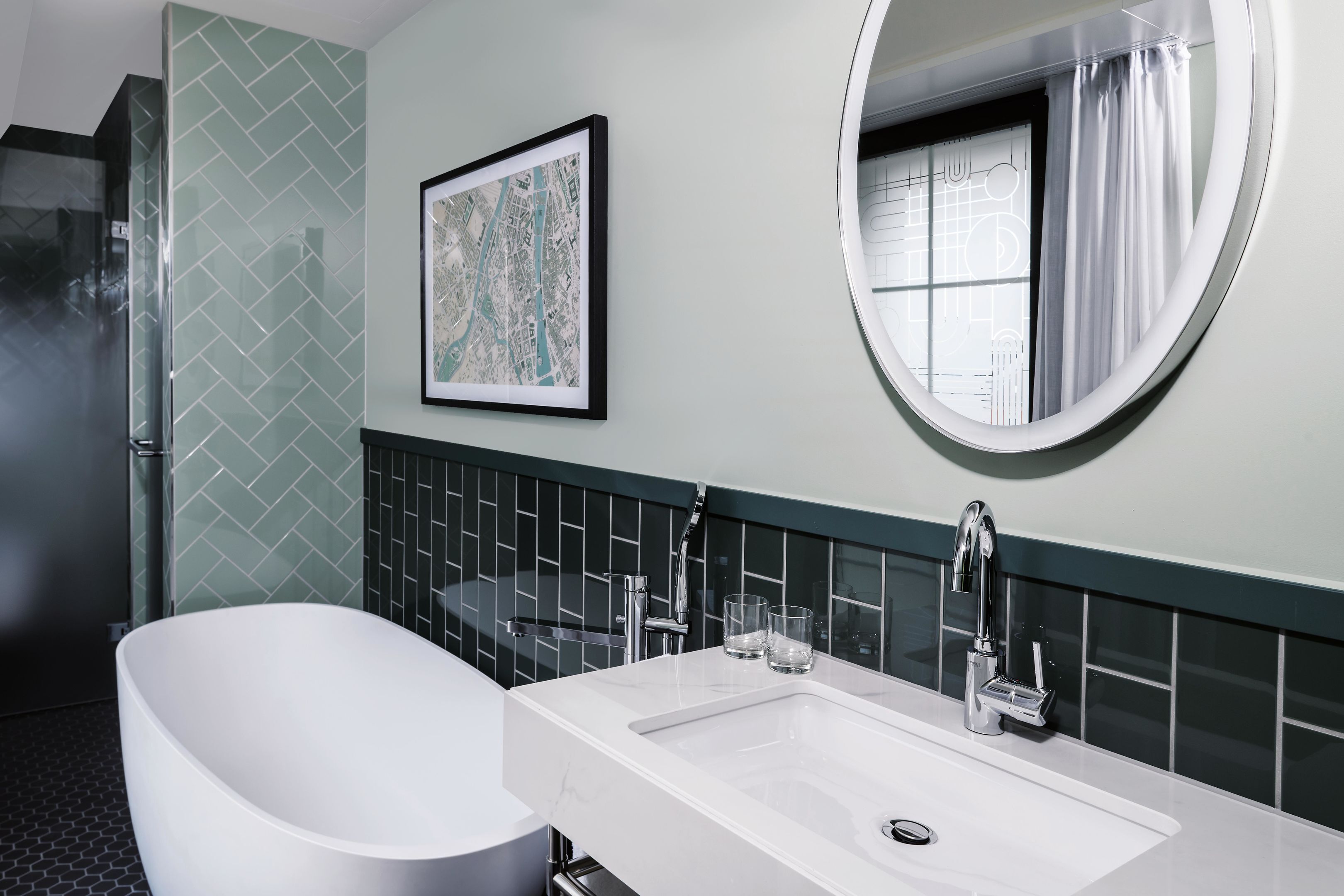Un baño moderno con una bañera independiente, un lavamanos rectangular, un espejo grande y un mapa enmarcado en la pared.