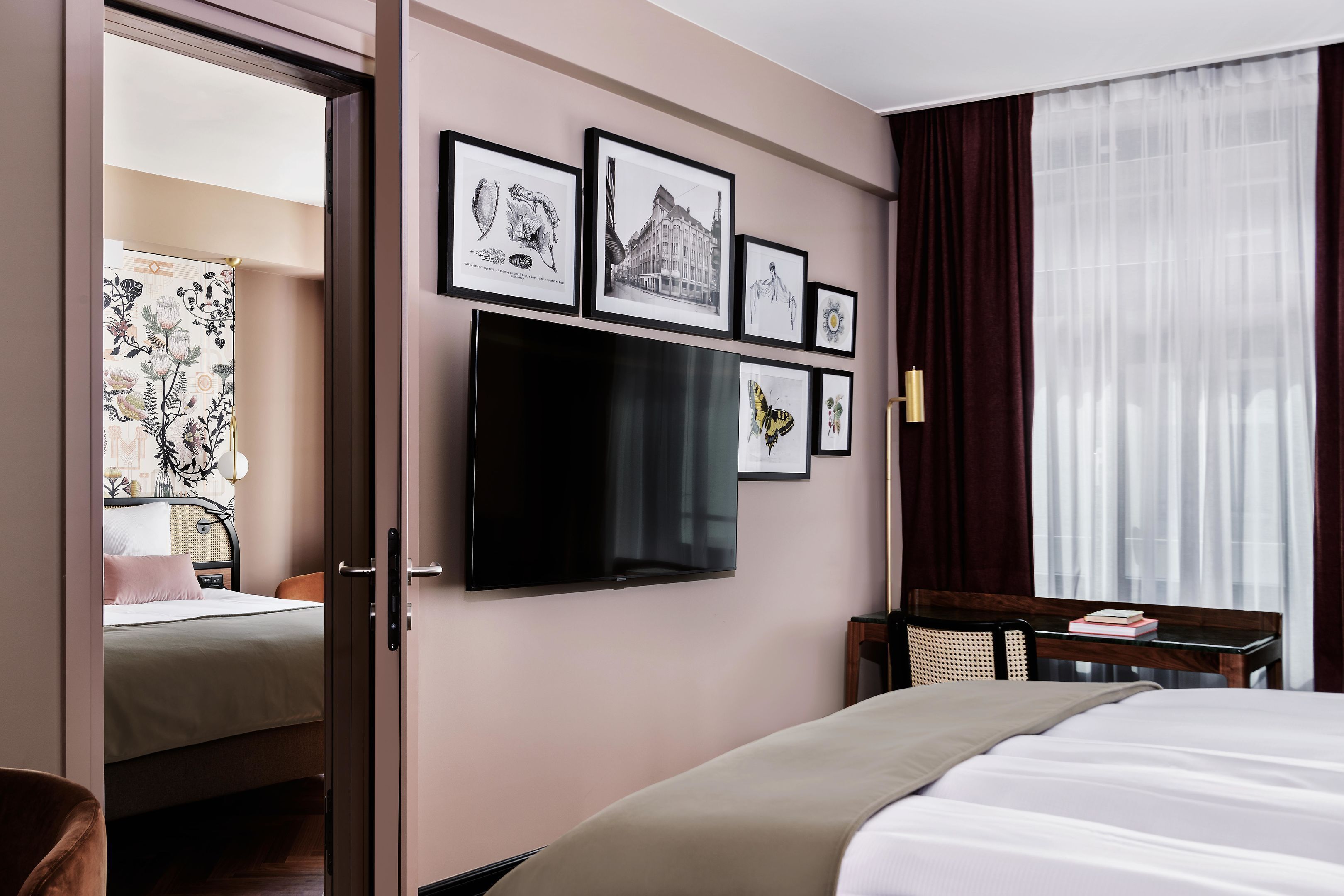 Ein Hotelzimmer mit einem Bett, einem Schreibtisch, einem Fernseher und gerahmten Bildern an der Wand.