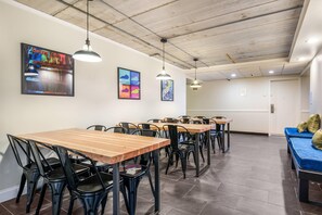 A dining area with tables and chairs, ceiling lights, and artwork on the walls.