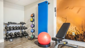 Un gimnasio con equipo de ejercicio, una banca y una pared con vistas.