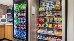 Máquina expendedora llena de bebidas y aperitivos, como refrescos y papas fritas.
