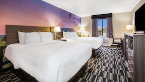 Habitación de hotel con dos camas, un escritorio, una silla y un televisor.