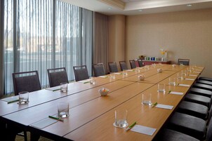 Un salón de conferencias con una larga mesa, sillas y vistas al exterior a través de amplios ventanales.