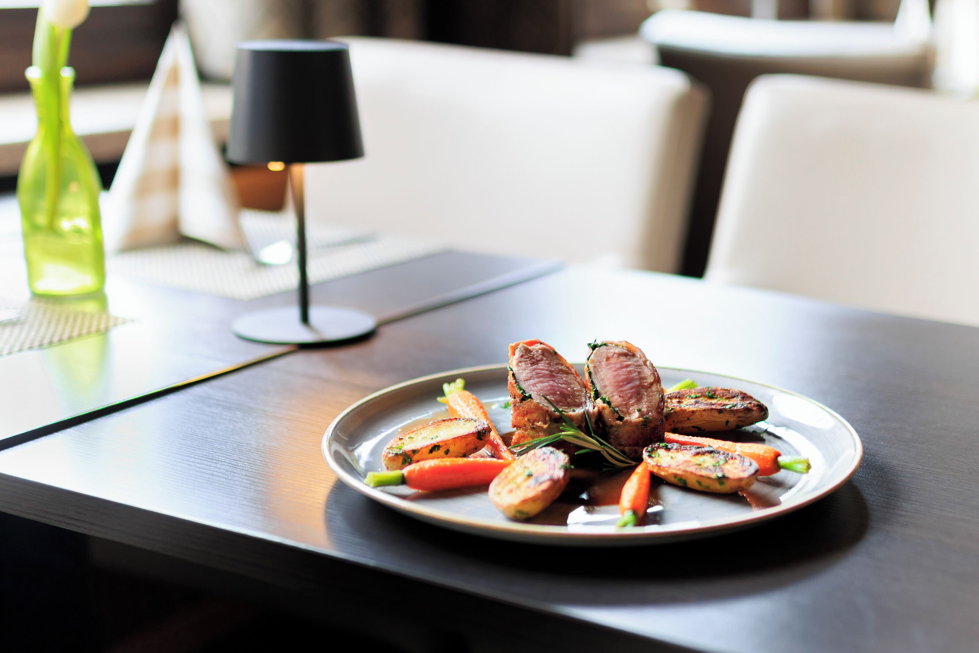 A plate of food on a table with a lamp in the background.