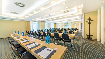 A conference room with long tables, chairs, water bottles, and a projector screen.