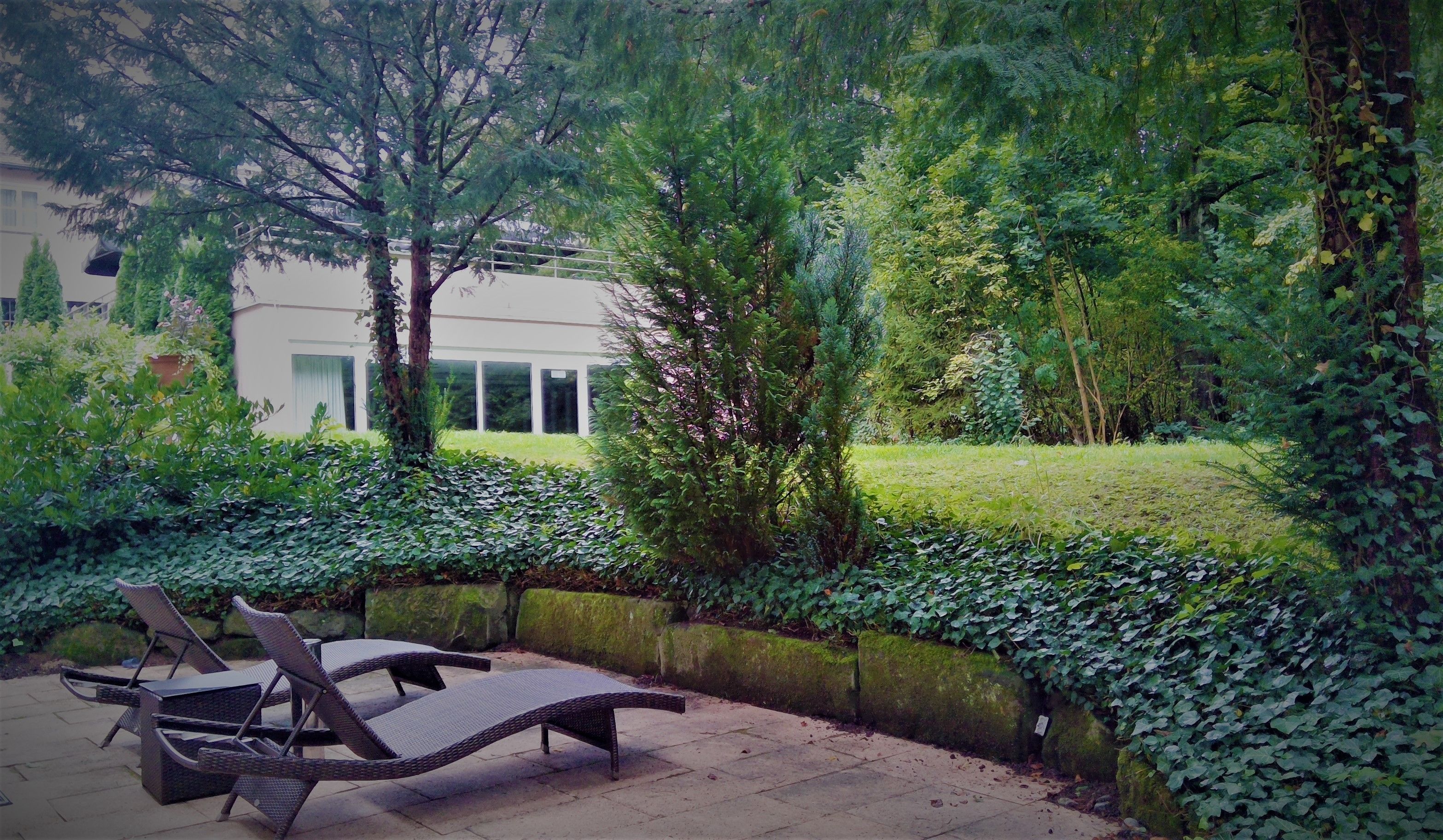 Un patio con sillones de mimbre y una pared de piedra.
