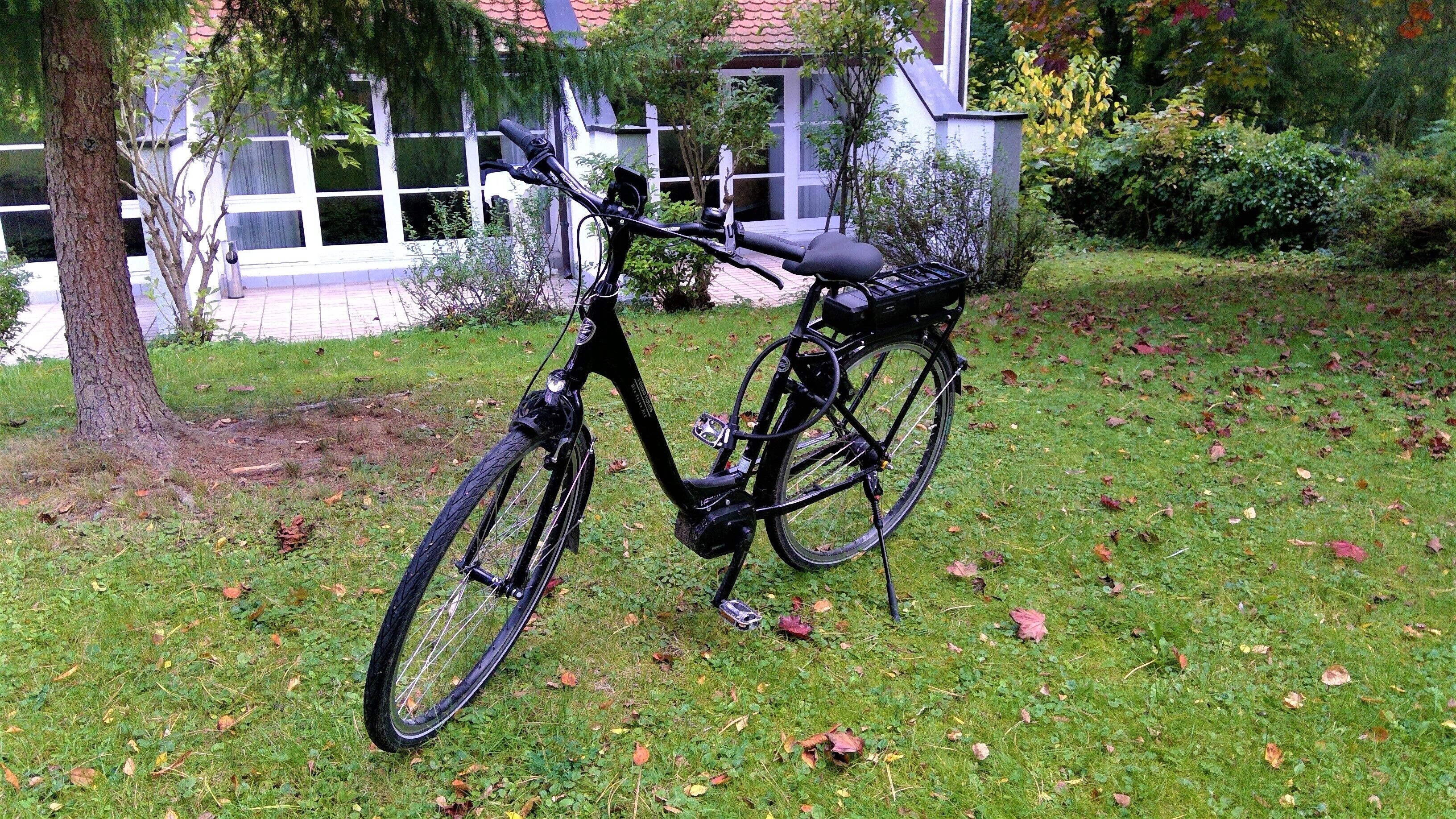Ein Fahrrad auf einer grünen Rasenfläche, im Hintergrund ein Haus.