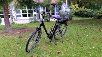 Ein Fahrrad auf einer grünen Rasenfläche, im Hintergrund ein Haus.