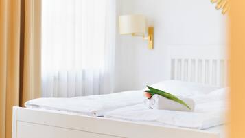 Ein Hotelzimmer mit einem ordentlich bezogenen Bett, einer Wandleuchte und einem Fenster mit Vorhängen.
