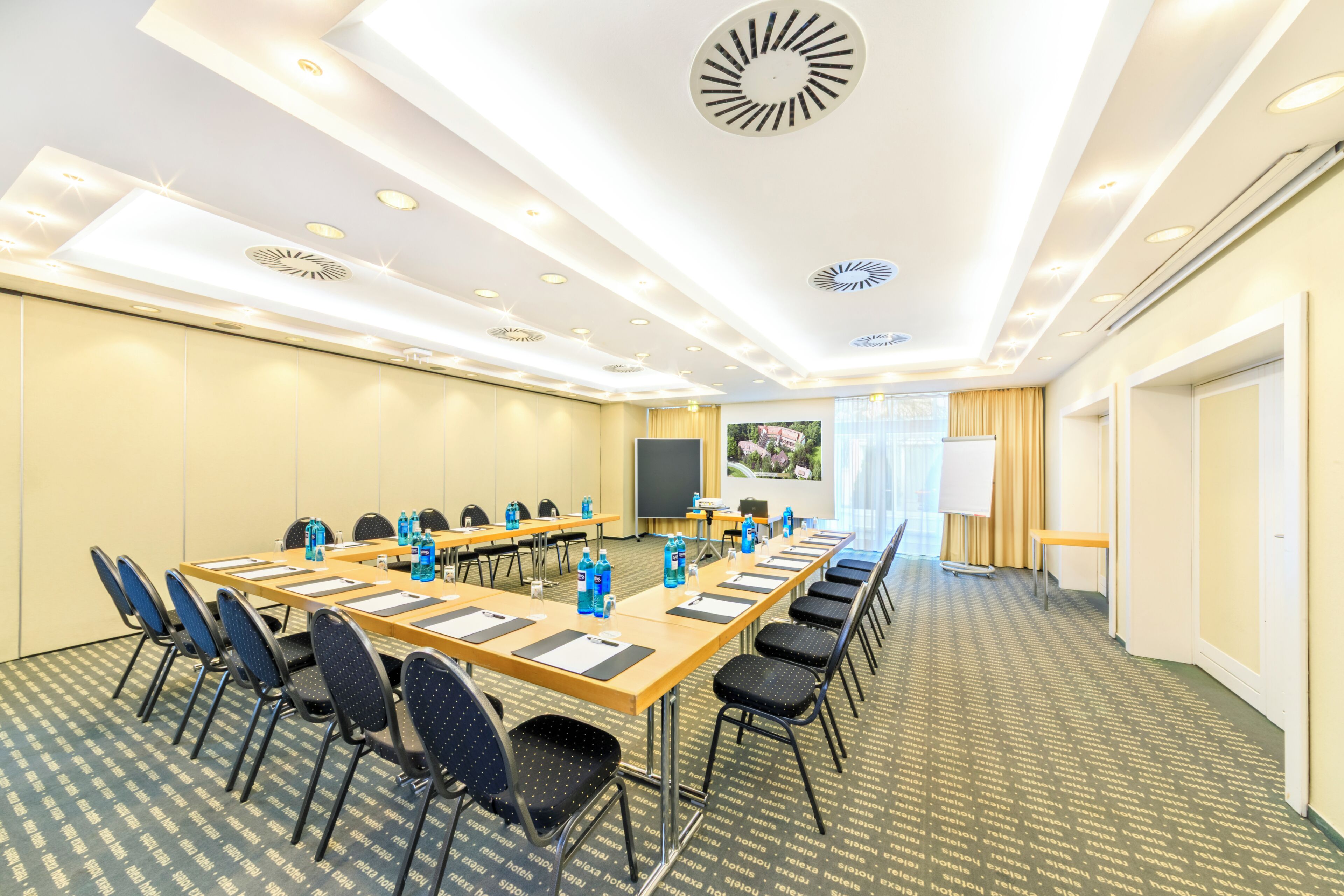 A conference room with a long table, chairs, a projector screen, and a whiteboard.