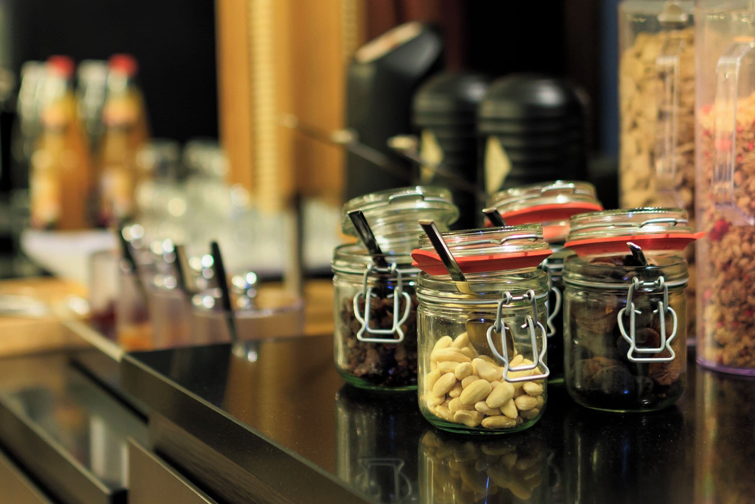 Una barra de buffet con diversos alimentos en frascos de vidrio.