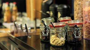 Una barra de buffet con diversos alimentos en frascos de vidrio.
