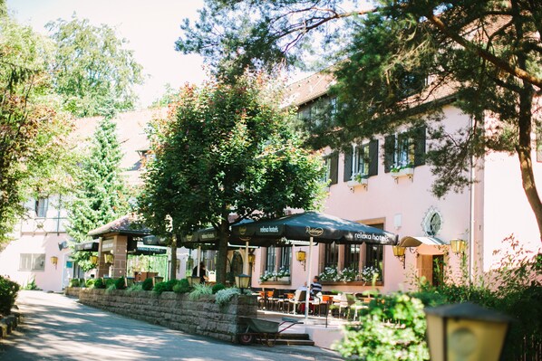 A hotel with outdoor seating, a stone wall, and a wheelbarrow. - relexa Waldhotel Schatten (Stuttgart)