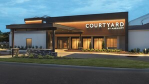 A modern Courtyard by Marriott hotel with a well-lit entrance, landscaped garden, and a clear sky. - Courtyard by Marriott Annapolis (Annapolis)