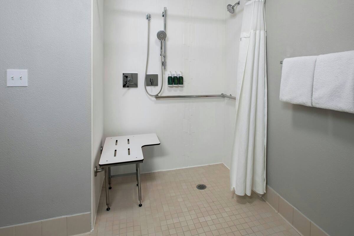 Un baño con ducha, una mesita y un perchero.