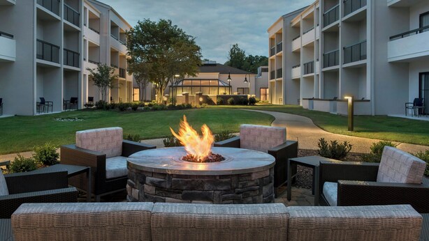 A courtyard with a stone fire pit surrounded by wicker furniture and a grassy lawn. - Courtyard by Marriott Annapolis (Annapolis)