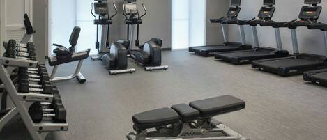 Un gimnasio con cintas de correr, elípticas y bancos de pesas.