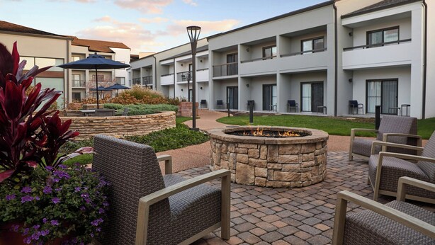 Un patio con mobiliario exterior, una chimenea y un jardín cuidado.