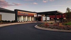 Un hotel Courtyard by Marriott con una fachada moderna, un acceso cubierto y jardines ajardinados.