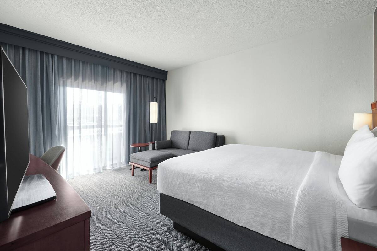 Ein Hotelzimmer mit einem großen Bett, einem Schreibtisch, einem Stuhl und einem kleinen Tisch.