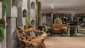A modern lobby with a large wooden sculpture, seating area, and a bar. - Hotel Paradox, Autograph Collection (Santa Cruz)